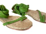 pair of women ' s sandals with green ribbons on them on a white surface