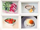 four paintings of food displayed in a white frame on a table