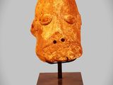 a close up of a sculpture of a head on a wooden stand