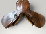 une paire de selles en cuir marron sur fond gris
