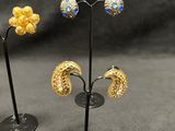 three pairs of earrings are displayed on a stand on a table