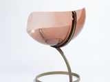 a pink glass vase on a metal stand on a white background