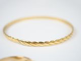 two gold rings with twisted edges on a white surface