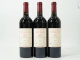 trois bouteilles de vin rouge sont alignées sur une surface blanche