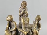 bronze figurines of people sitting on top of a pile of books