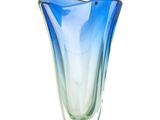 un vase en verre bleu et vert posé sur une surface blanche