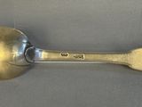 silver spoon with a gold handle on a gray surface