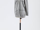 un pull gris posé sur un mannequin, devant un fond blanc