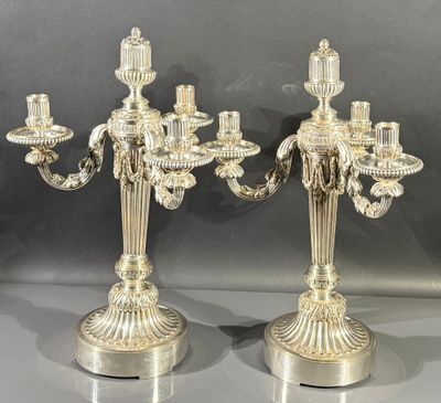 paire de chandeliers plaqués argent avec des bougies sur leurs socles