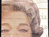 a woman standing in front of a wall with a poster on it