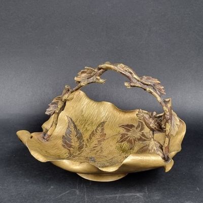 brass plate with leaves and flowers on it on a black surface