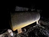 un grand réservoir métallique posé au milieu d'un champ, la nuit