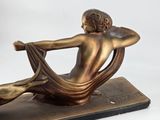 bronze statue of a woman sitting on a chair with her back to the camera