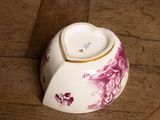 a white and purple bowl with a gold rim on a wooden floor