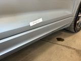 the rear end of a silver car with a sticker on it