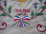 embroidery on a table cloth with a cup and ribbon on it