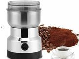 un gros plan d'un moulin à café à côté d'une tasse de café