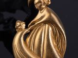 un pendentif en or représentant une femme tenant un enfant dans ses bras, sur un fond noir