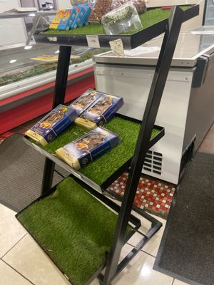 une vitrine dans une épicerie dont les étagères sont recouvertes d'herbe