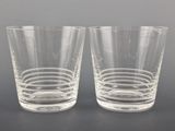 two clear glasses sitting on top of a table next to each other