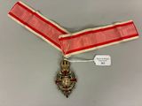 une image représentant un ruban rouge et blanc sur lequel est accrochée une médaille d'or