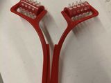 deux brosses à dents en plastique rouge posées sur un plan de travail blanc