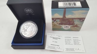 une pièce d'argent dans une boîte, accompagnée d'un ticket correspondant