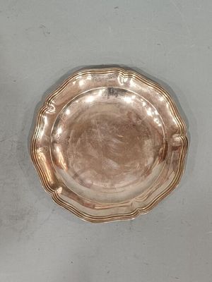 une assiette en argent posée sur une table, sur fond blanc