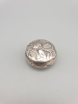 un petit bouton en argent orné d'un motif floral