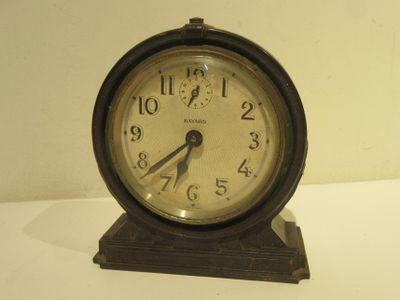 une petite horloge posée sur une table blanche