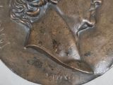 a silver medal with a woman ' s face on it