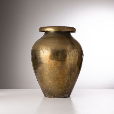 un grand vase en or posé sur une table blanche