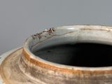 a white vase with a brown rim sitting on a table