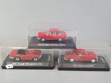 three red die cast cars in clear boxes on a white surface