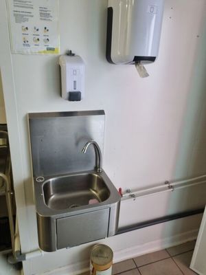 un évier dans un coin de la cuisine, avec un distributeur d'eau fixé au mur