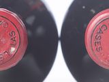 two bottles of red wine sitting next to each other on top of a table