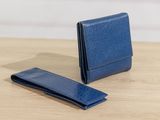 a blue leather wallet and money clip on a wooden table