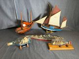 trois bateaux miniatures et une bouteille posés sur une table