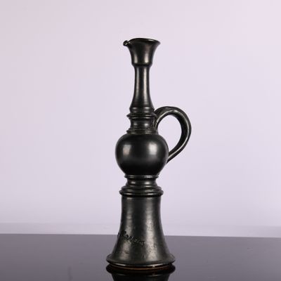 un vase noir posé sur une table, sur fond blanc