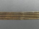 a close up of a gold and black striped bracelet on a gray surface