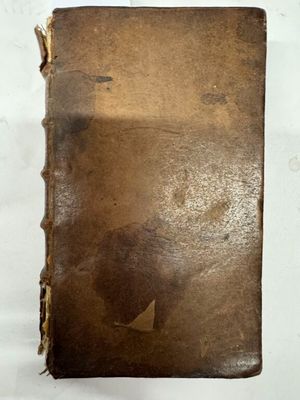 un vieux livre avec un trou au milieu, posé sur une surface blanche
