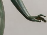 bronze statue of a woman ' s hand holding a flower in her left hand