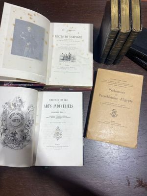 Plusieurs vieux livres sont posés sur une table, à côté d'une pile de vieux livres