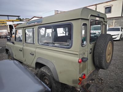 une jeep verte garée sur un parking à côté d'un immeuble