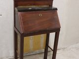 a small wooden writing desk with a glass top
