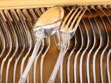 a lot of forks and spoons that are on a rack