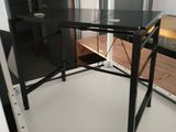 a glass desk with a black top and a black chair