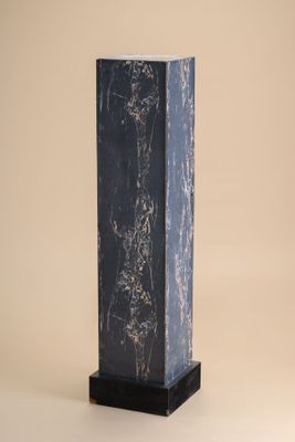 black marble column with a black base on a beige background