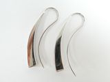 une paire de boucles d'oreilles en argent et en bois posées sur une surface blanche