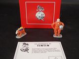 deux figurines représentant deux astronautes devant une boîte rouge